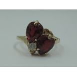 A lady's dress ring having two ruby style teardrop stones in claw set heart mounts with a clear