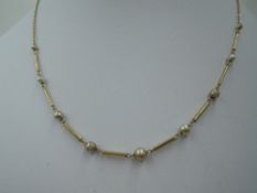 A yellow metal necklace stamped 9K having simulated pearls with tube connectors on a fixed chain, (