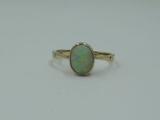 A lady's dress ring having an oval opal in a collared mount on a rose gold loop stamped 9ct, size I