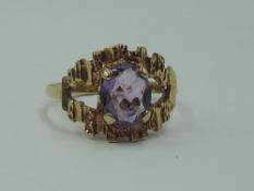 A lady's dress ring having an oval amethyst in a stylised open mount on a 9ct gold loop, size N &