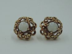 A pair of 9ct gold stud earrings having central opal cabouchons in a shaped pierced mount