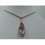 A large amethyst pendant in a yellow metal tear drop shaped open mount stamped 9ct on a 9ct gold