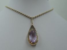 A large amethyst pendant in a yellow metal tear drop shaped open mount stamped 9ct on a 9ct gold