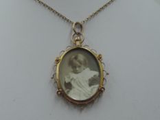 A glass locket of oval form having a decorative 9ct gold mount on a yellow metal chain stamped