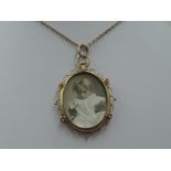A glass locket of oval form having a decorative 9ct gold mount on a yellow metal chain stamped