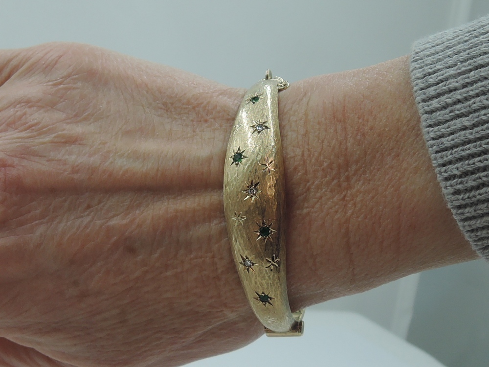 A 9ct gold hinged bangle having diamond and emerald chip decoration in star burst settings on - Image 2 of 3