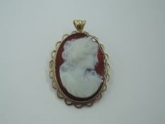 A carved agate cameo brooch/pendant depicting a maiden in profile on an orange agate ground in a 9ct