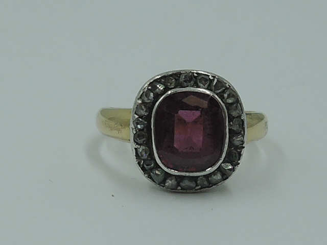 A lady's dress ring having a central pink stone possibly tourmaline in a collared mount with diamond