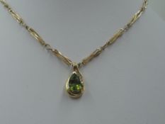 A peridot tear drop shaped pendant having diamond chip decoration in a yellow metal mount stamped 9K