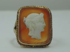 A lady's dress ring having a cameo plaque on orange agate, in a square yellow metal mount on