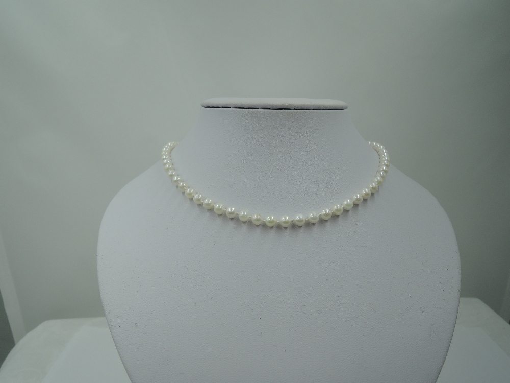 A string of cultured pearls of even form having a yellow metal clasp stamped 9K, approx 16'