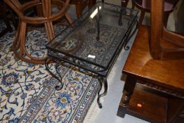 A low wrought iron and glass topped coffee table H42cm x D37cm x 76cm