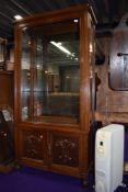 An early 20th Century oak display cabinet, having side opening doors, and cupboard base, width