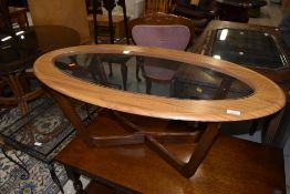 An oval teak effect coffee table with glass centre