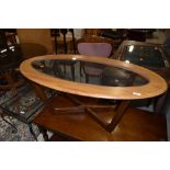 An oval teak effect coffee table with glass centre