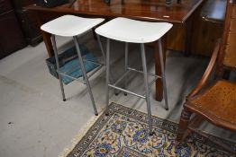 A pair of modern bar or kitchen stools with white vinyl tops