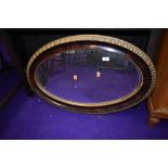 A vintage gilt and rosewood effect oval wall mirror