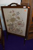 A traditional oak firescreen having embroidered panel