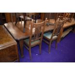 An early 20th Century dark oak wind out dining table and set of four high back dining chairs in