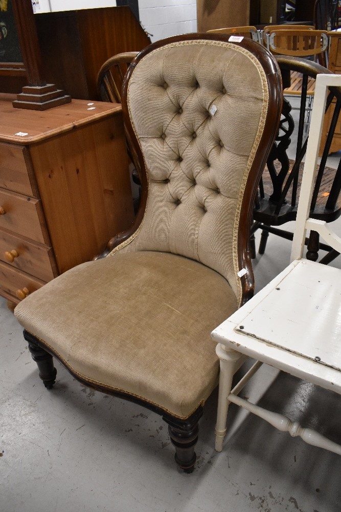 An antique nurising chair having button back and turned frame feet