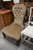 An antique nurising chair having button back and turned frame feet