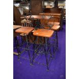 A wrought iron high table, and two matching chairs and two matching stools, having wooden seats