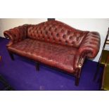 A traditional oxblood button back leather settee, having shaped back, width approx. 200cm