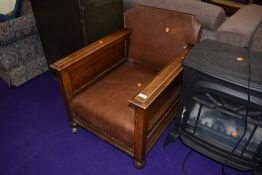 An early 20th Century oak and brown leather easy chair on later shepherds castors