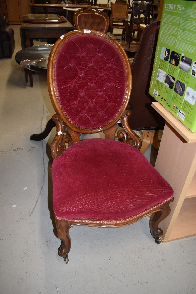 A Victorian button back salon or nursing chair having scroll work frame on cabriole legs