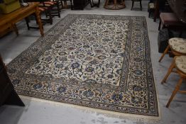 A large wool woven rug or carpet square in cream and blue green grounds in a Kashan design 344cm x