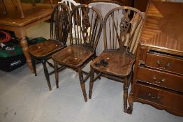 A set of three traditional farm or country house style elm and ash wheelback dining chairs