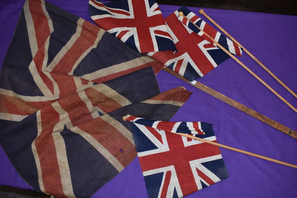 Two hand held British flags and similar larger Union Jack flag possibly military related