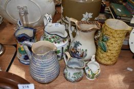 A selection of pressed moulded and similar water jugs of various designs including Majolica styled