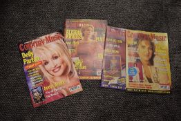 A collection of country music magazines and two cases.