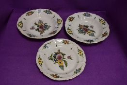 Two bowls and a plate decorated in English Delft styles with heavy glaze and floral scenes all