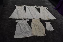 A selection of antique items of baby clothing including one long gown with cut work and