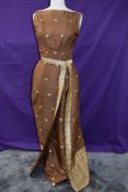 A vintage full length 1950s dress having gold thread motifs on a copper coloured silk or silk