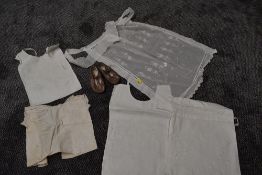 A pair of 1920s childrens shoes,and a bib and an apron of a similar age.