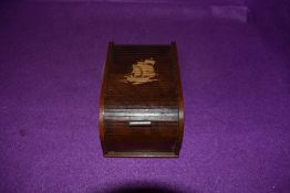 A vintage wooden roll top cigarette case with kinetic internal movement,having ship design to top.