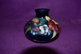 An antique balluster squat vase by Moorcroft bearing signature to base painted with Orchid on blue