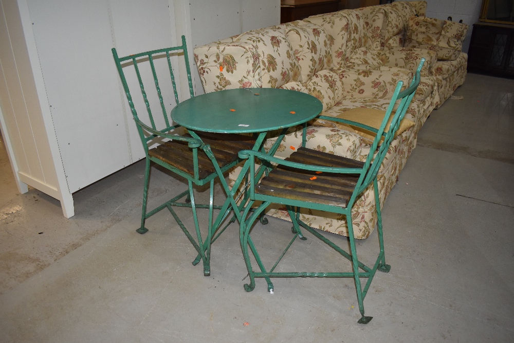 A metal garden table (probably painted aluminium) and two painted wrought iron stylised garden