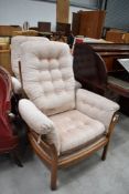 Two modern Ercol wing back arm chairs in a medium stain