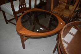 A vintage teak effect coffee table of stylised form having smoked glass top