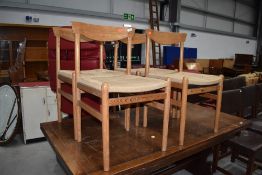 A set of four vintage pine kitchen dining chairs having strung seats and shaped single rail,