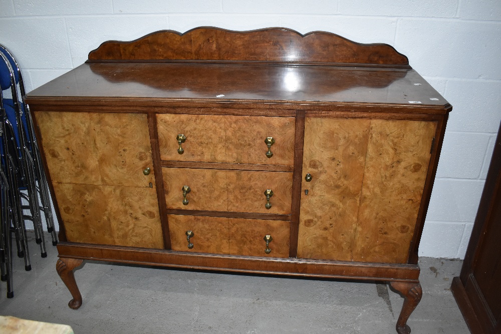 An early to mid 20th Century burr walnut sideboard having three central drawers flanked by cupboards