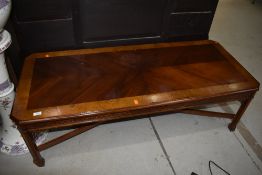 A reproduction mahogany and yew wood coffee table, having canted corners, blind fretwork frieze on