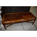 A reproduction mahogany and yew wood coffee table, having canted corners, blind fretwork frieze on