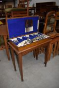 An early 20th Century oak cutlery canteen on square tapered legs, includes contents of mainly plated