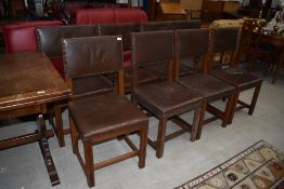 A traditional set of eight (six plus two) oak dining chairs having brown leather seats and backs