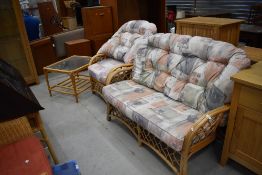 A modern cane conservatory suite comprising settee , chair and glass topped coffee table